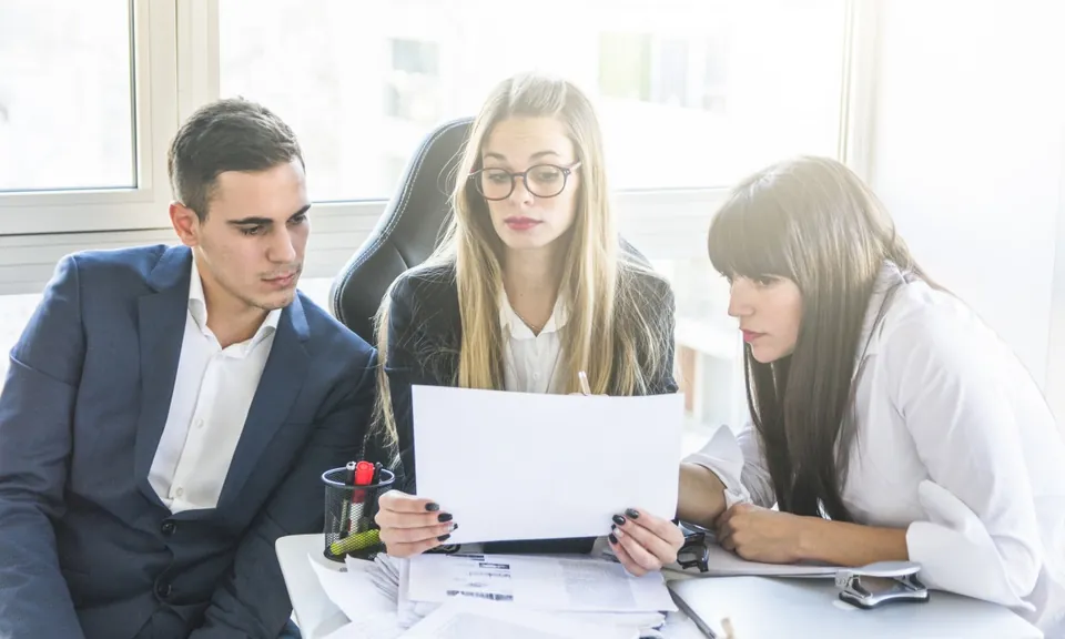 Drie collega's lezen samen een document
