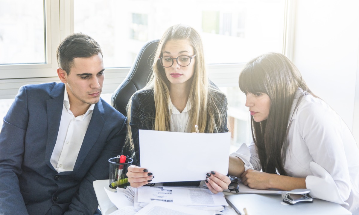 Drie collega's lezen samen een document